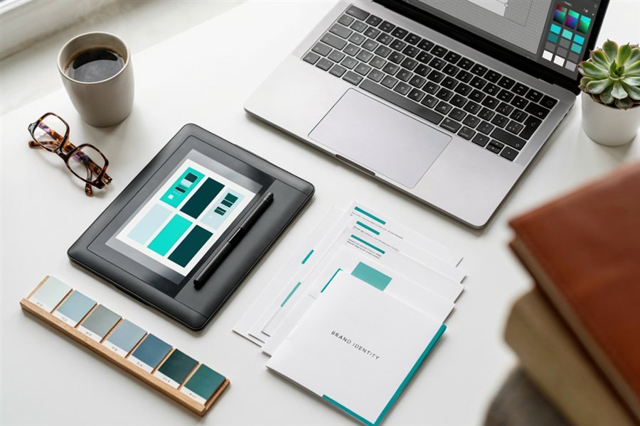 Mesa de trabajo con paleta de colores, tablet gráfica y carpeta de identidad de marca